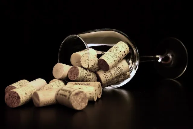 Picture of a glass on its size with bottle corks spilling out of it for how to clean cork coasters