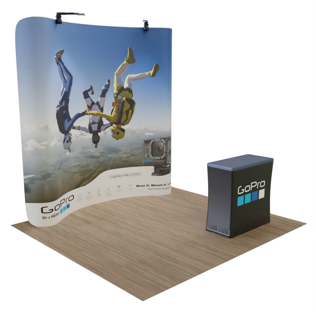 This is a trade show display featuring a backdrop with an image of skydivers and a counter with branding, set against an implied exhibition setting.